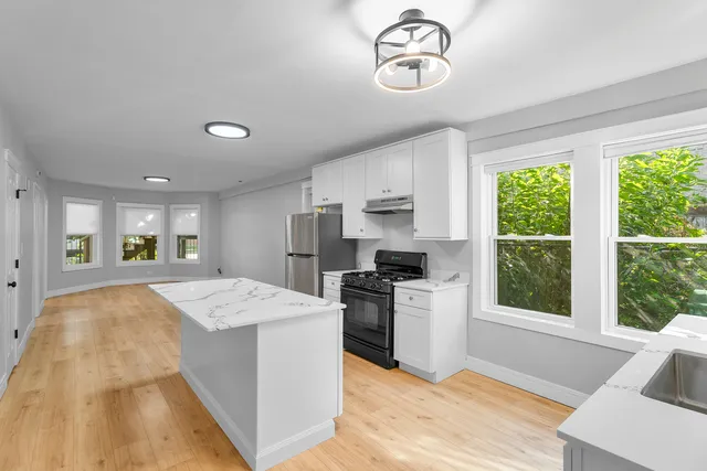 a open kitchen with kitchen island granite countertop a stove and a refrigerator