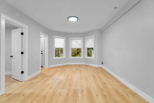 a view of an empty room with window and wooden floor
