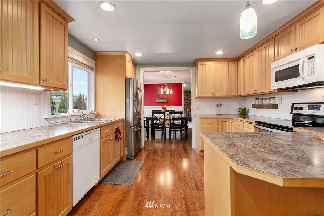 2091 Zell Road Ferndale, WA 98248 - Photo 8 of 25 a kitchen with stainless steel appliances granite countertop a stove top oven a sink a dining table and chairs with wooden floor