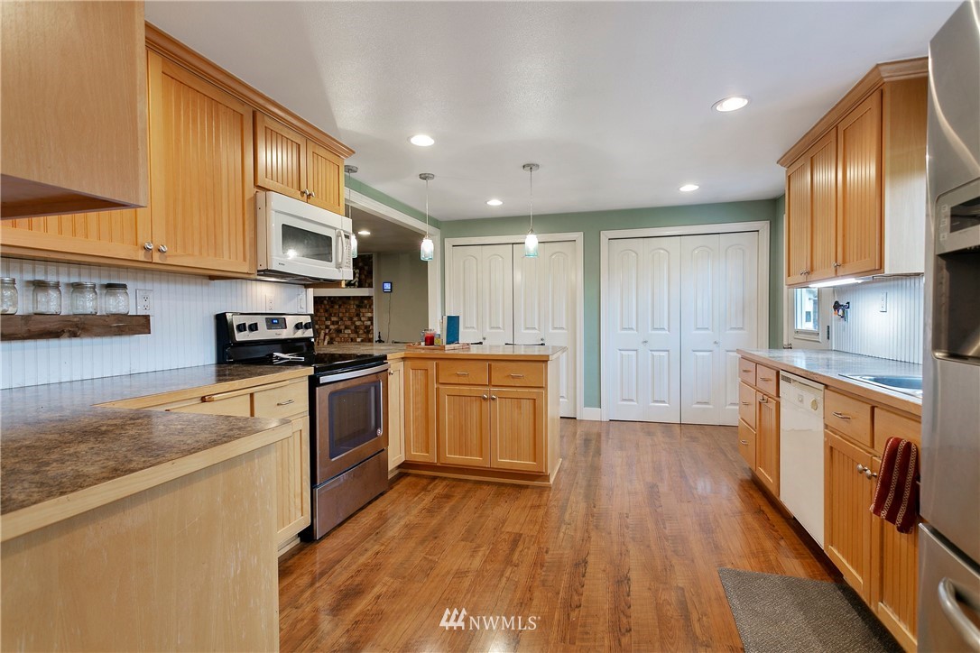 2091 Zell Road Ferndale, WA 98248 - Photo 9 of 25 a kitchen with stainless steel appliances granite countertop wooden cabinets a refrigerator a sink a stove a microwave and wooden floors