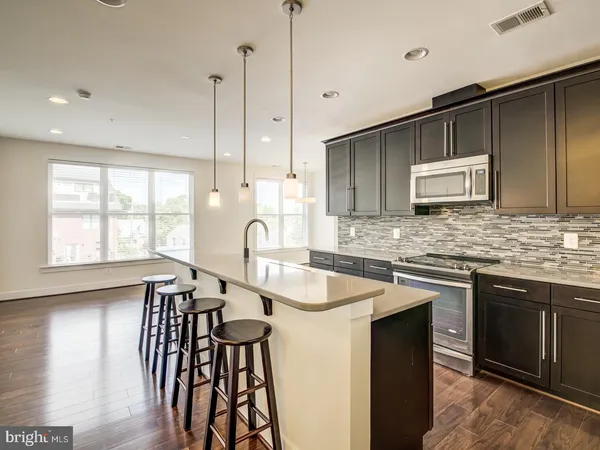 a kitchen with stainless steel appliances granite countertop a sink a stove a refrigerator cabinets and wooden floor