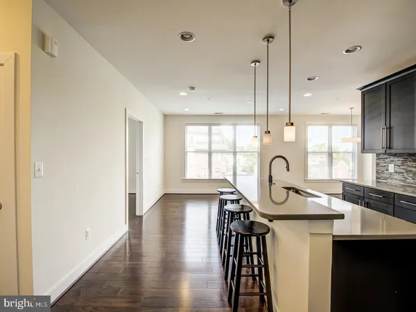 a kitchen with stainless steel appliances a table chairs in it and wooden floors
