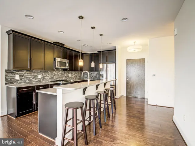 a kitchen with stainless steel appliances granite countertop wooden floor a refrigerator a sink a stove and a microwave