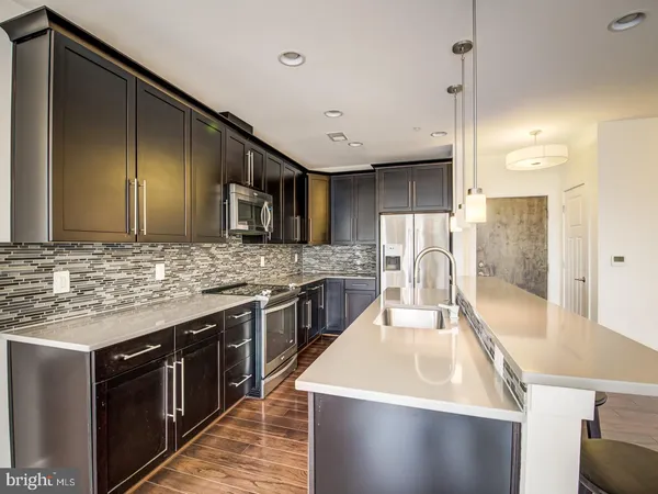 a large kitchen with stainless steel appliances wooden cabinets and a counter top space