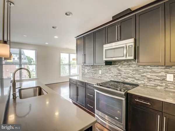 a kitchen with granite countertop a stove a sink and a microwave