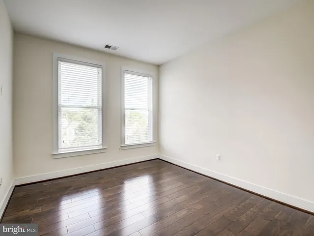 an empty room with wooden floor and window