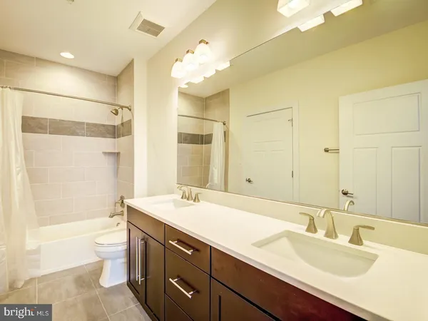 a bathroom with a double vanity sink toilet mirror and shower