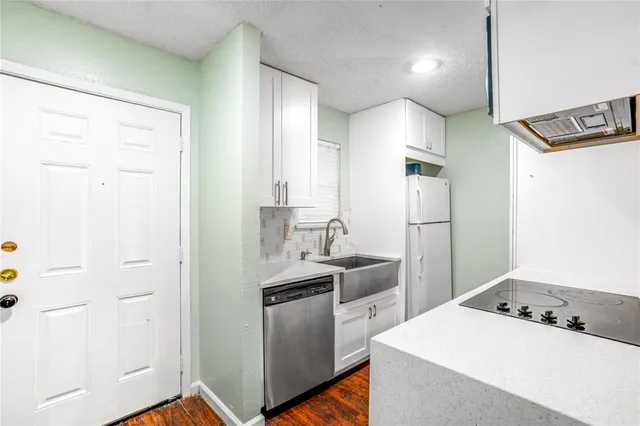 a kitchen that has a sink a refrigerator and a stove top oven
