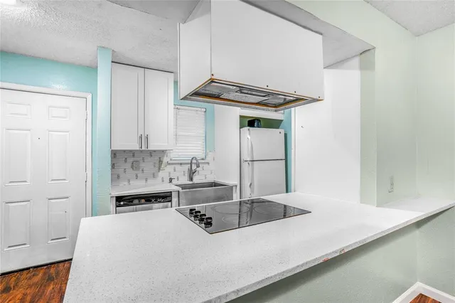 a kitchen with kitchen island a sink a stove and white cabinets