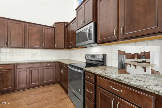 a kitchen with kitchen island granite countertop a stove top oven a sink and dishwasher