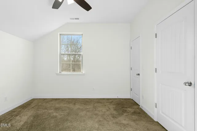 an empty room with a chandelier fan and windows
