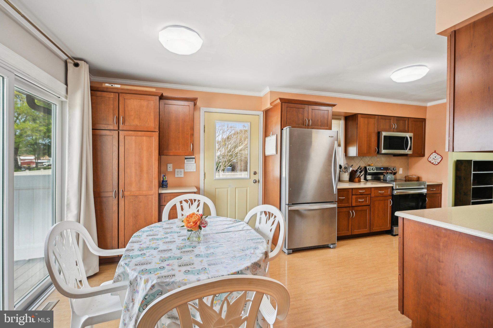 205 Lehigh Road South Glassboro, NJ 08028 - Photo 22 of 51 a kitchen with stainless steel appliances granite countertop a refrigerator a stove top oven a sink with a dining table and chairs