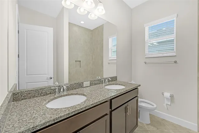 a bathroom with a granite countertop double vanity sink and a mirror
