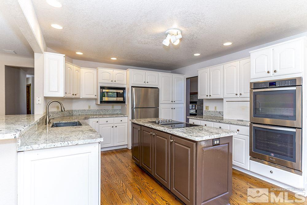 725 Arius Court Reno, NV 89512 - Photo 10 of 27 a kitchen with stainless steel appliances granite countertop a stove top oven a refrigerator a sink and dishwasher with wooden floor