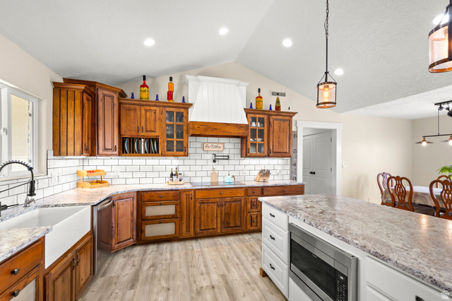 2591 East Washington Dam Road Washington, UT 84780 - Photo 13 of 67 Kitchen featuring wood cabinetry, white subway tile backsplash, light-toned countertops, a farm sink, and an integrated microwave in the island
