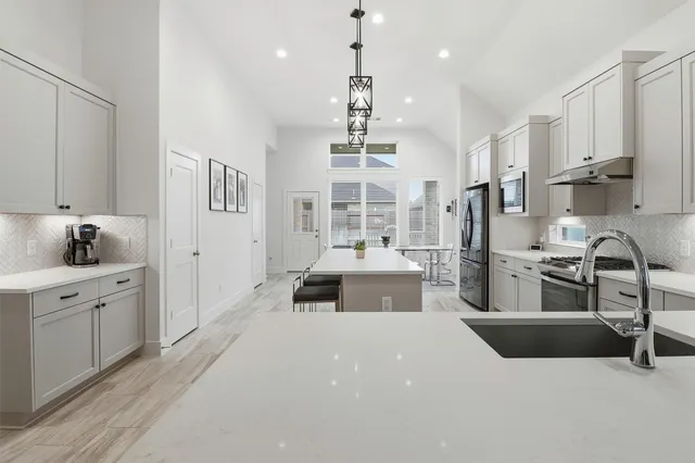 a large kitchen with kitchen island a large counter space a sink stainless steel appliances and cabinets
