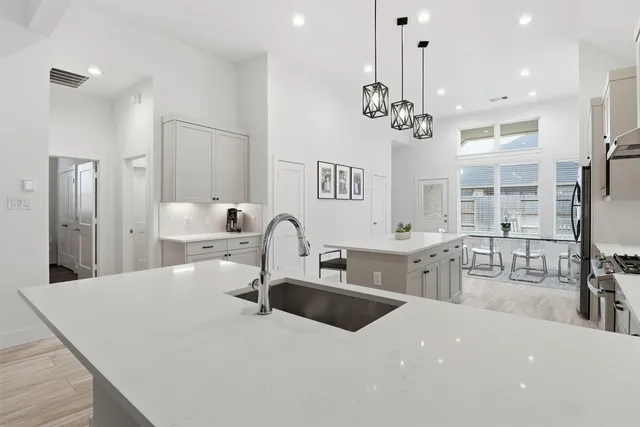 a kitchen with stainless steel appliances a sink dishwasher a refrigerator and a dining table with wooden floor