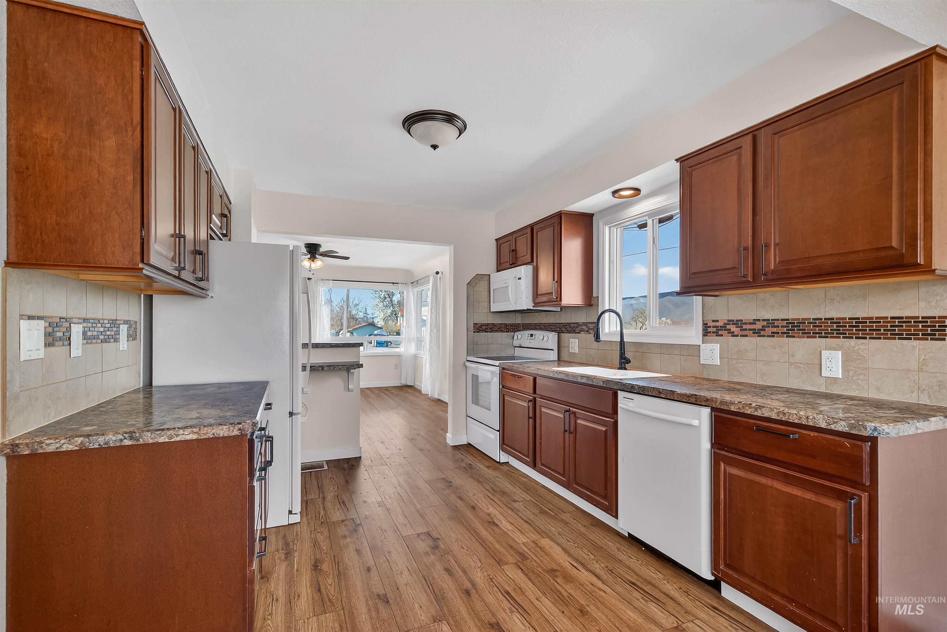 1519 17th Street Lewiston, ID 83501 - Photo 12 of 39 Kitchen with backsplash, white appliances, wood finish cabinets, light wood finished floors, and a ceiling fan