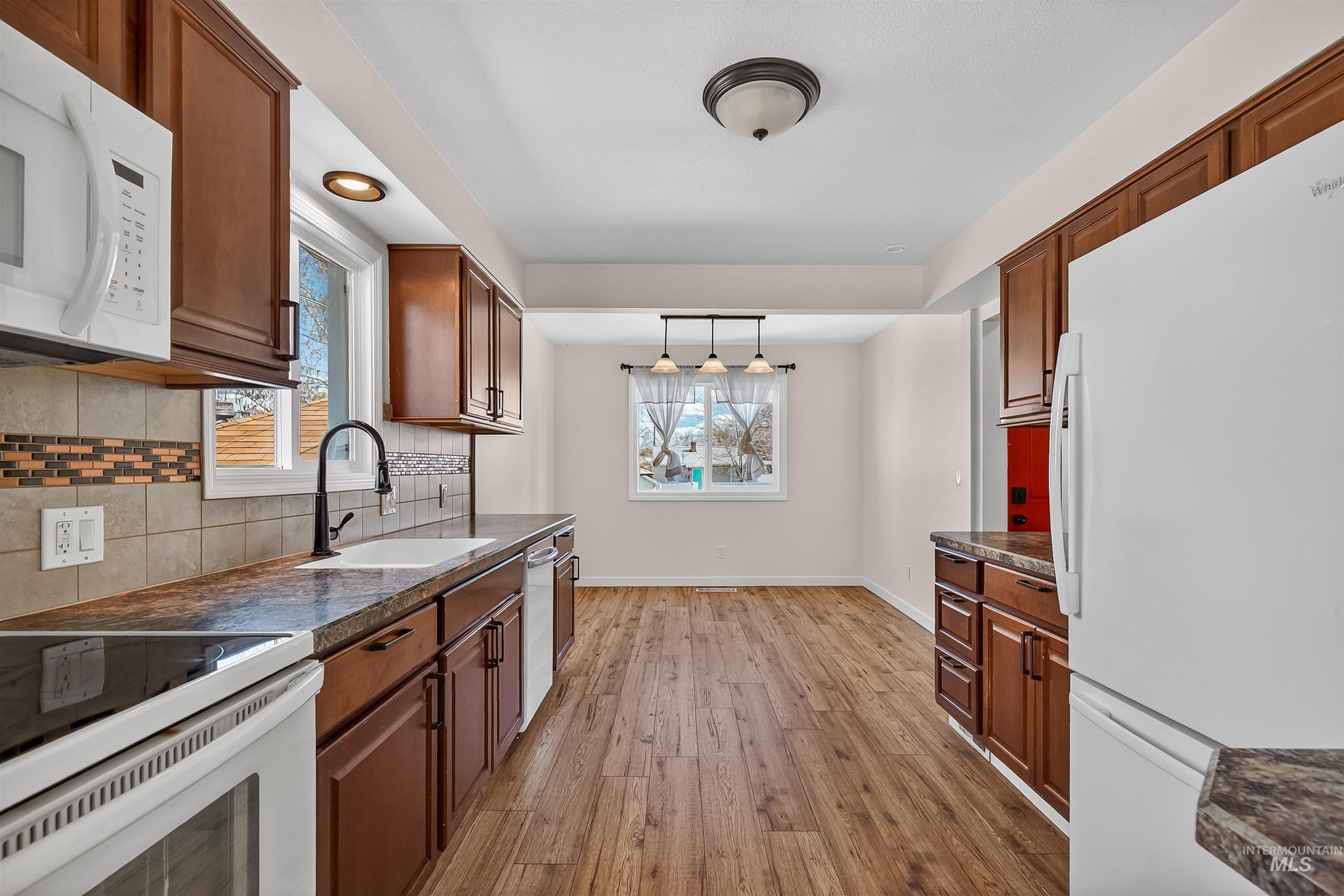 1519 17th Street Lewiston, ID 83501 - Photo 13 of 39 Kitchen featuring dark countertops, white appliances, light wood-style flooring, and wood finish cabinets