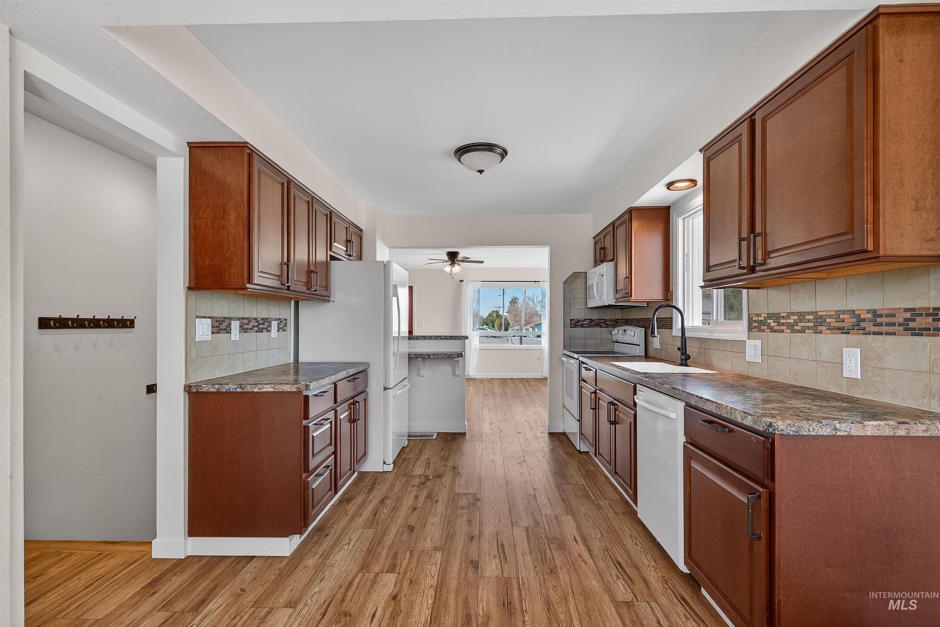 1519 17th Street Lewiston, ID 83501 - Photo 10 of 39 Kitchen featuring wood finish cabinets, white appliances, light wood finished floors, backsplash, and ceiling fan