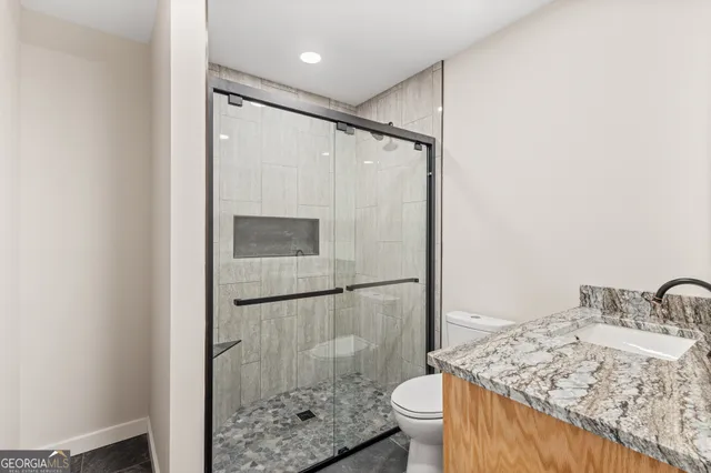 a bathroom with a granite countertop sink toilet and shower