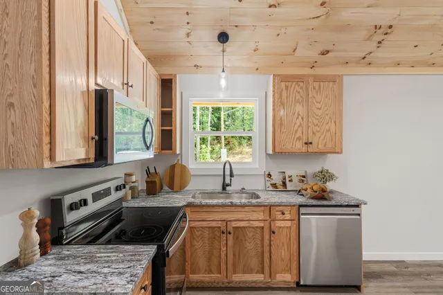 a kitchen with stainless steel appliances granite countertop a stove a sink and a microwave