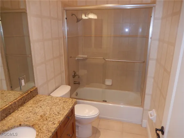 a bathroom with a granite countertop bathtub sink vanity mirror and toilet