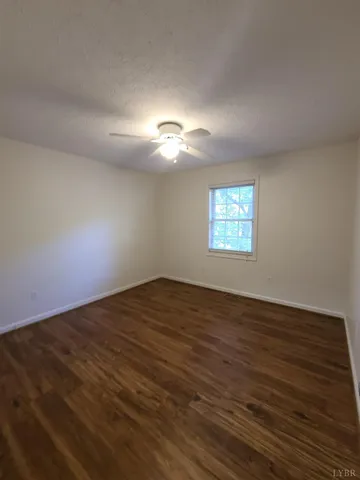 a view of a big room with wooden floor and a window