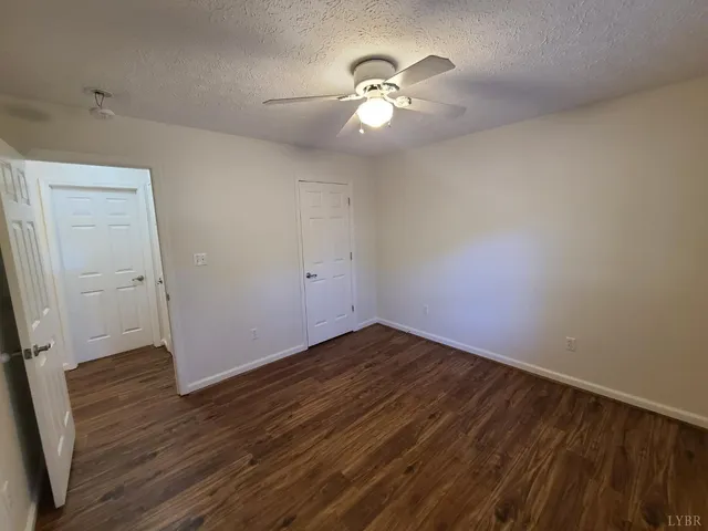 an empty room with wooden floor and chandelier fan