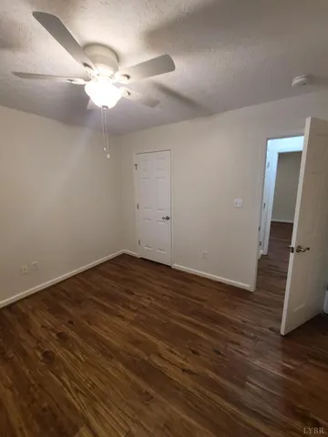an empty room with wooden floor and fan