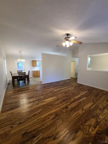 a view of a room with wooden floor chandelier fan and windows