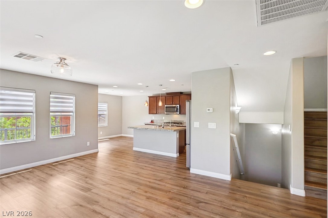 9940 Sable Point Street Las Vegas, NV 89178 - Photo 39 of 40 Kitchen with stainless steel microwave, open floor plan, light wood finished floors, brown cabinets, and recessed lighting