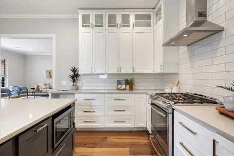 a kitchen with stainless steel appliances white cabinets and wooden floor