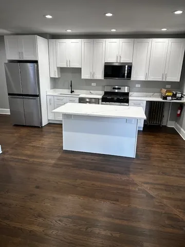 a kitchen with stainless steel appliances granite countertop a stove a refrigerator a sink and a microwave