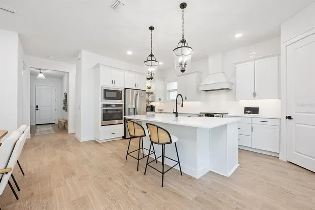 a kitchen with stainless steel appliances kitchen island granite countertop a table chairs refrigerator and microwave