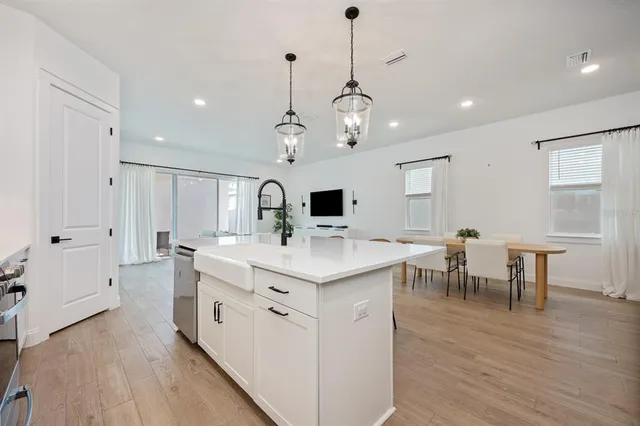 a open kitchen with stainless steel appliances granite countertop a stove and chairs with wooden floor