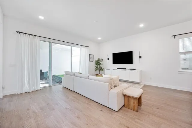 a living room with furniture a flat screen tv and a large window