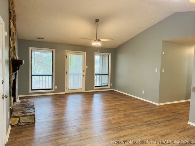 a view of an empty room with window and wooden floor