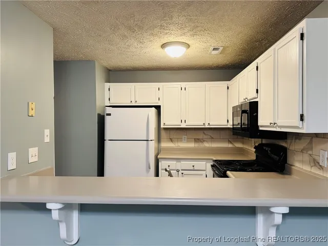 a kitchen with stainless steel appliances a refrigerator sink stove and white cabinets