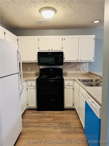 a kitchen with a refrigerator stove and white cabinets