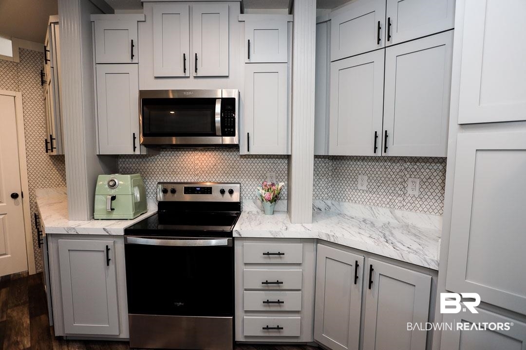 19180 Horseshoe Circle Seminole, AL 36574 - Photo 13 of 38 Kitchen featuring appliances with stainless steel finishes, gray cabinets, light stone countertops, tasteful backsplash, and dark wood-style flooring