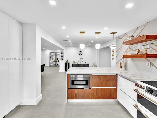 a room with kitchen island a dining table chairs and a chandelier