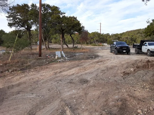a view of car parked on a road near a forest