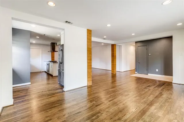 a view of a big room with wooden floor and a kitchen