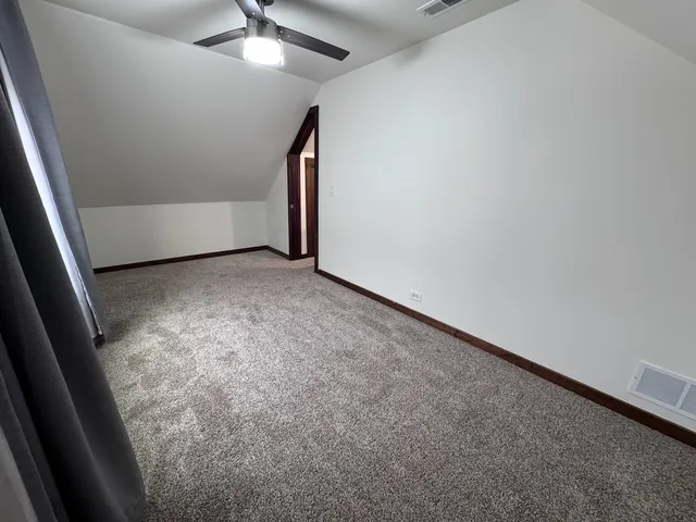 an empty room with a ceiling fan and carpet