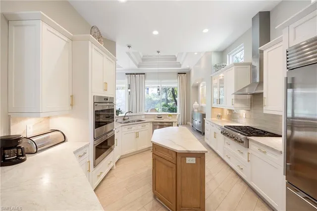 a large white kitchen with stainless steel appliances granite countertop a stove and a sink
