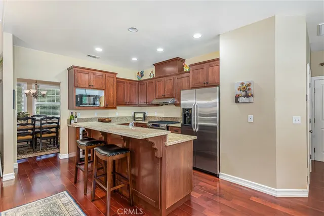 a kitchen with stainless steel appliances granite countertop a refrigerator a stove and a wooden floors