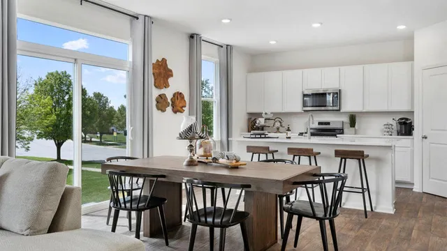 a dining room with furniture a floor to ceiling window and kitchen view