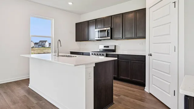a kitchen with a sink a stove top oven and wooden floor