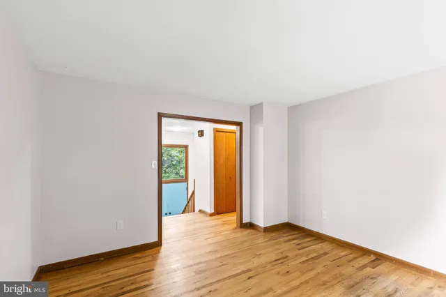 a view of an empty room with wooden floor and closet